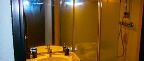 A bathroom with a glass-enclosed shower, a sink with a mirror above it, and a cabinet below.