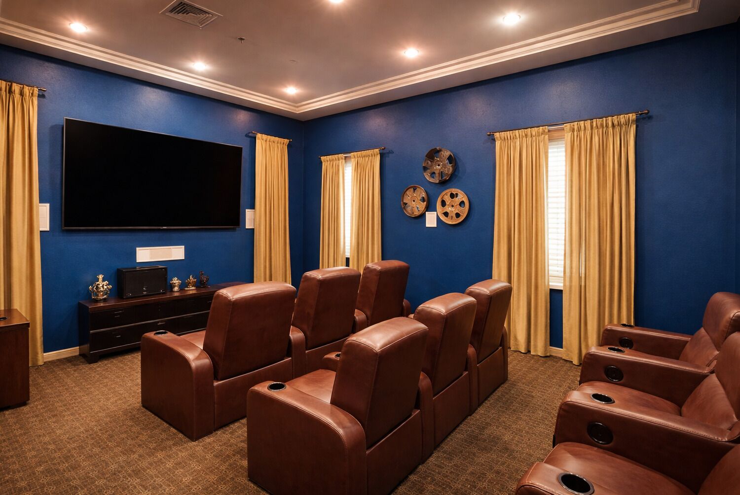 Una sala de cine en casa con paredes azules, un televisor de pantalla plana grande, asientos reclinables de cuero marrón y piso alfombrado.
