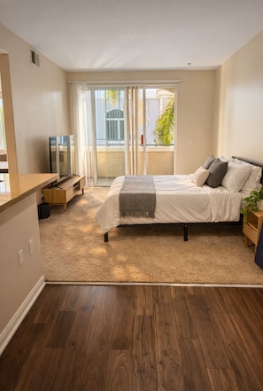 A bedroom with a bed, a TV, a balcony, and a wooden floor. - 1 Bedroom 1 Bathroom Marina Del Rey Unit (Marina del Rey)