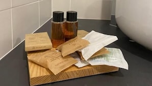 Une salle de bain avec un plan de toilette noir, un lavabo blanc et un pare-feu en carreaux à motifs.