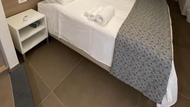 Une chambre d’hôtel avec un grand lit, une table de chevet et une commode, ainsi qu’une porte.