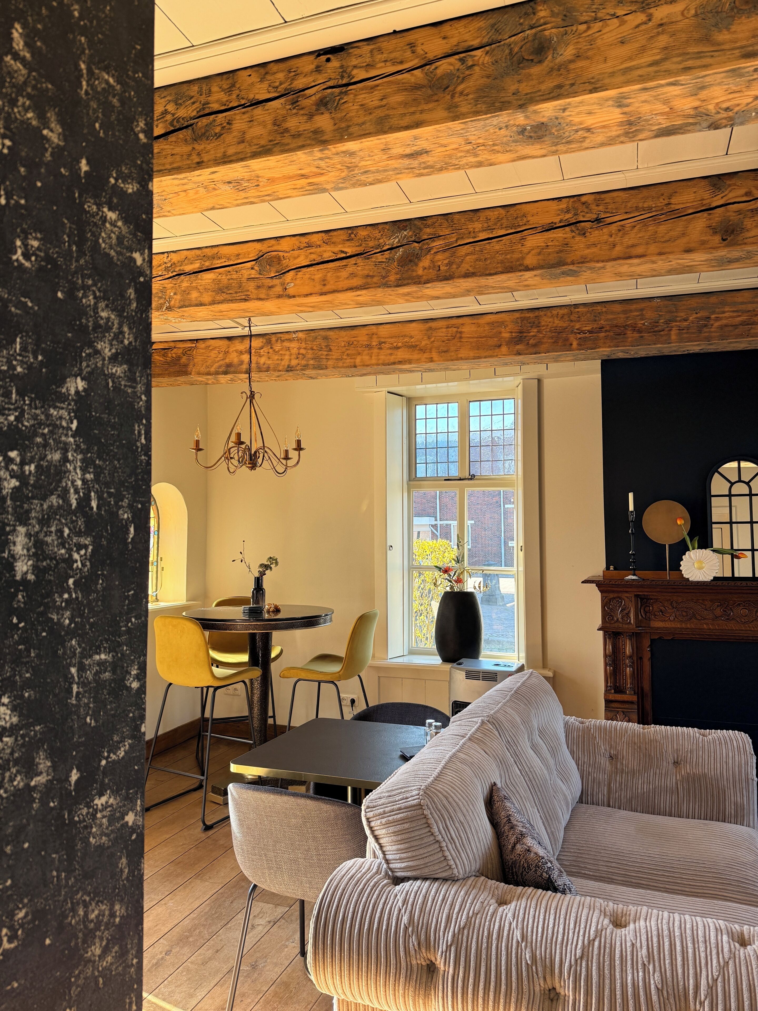 Een gezellige kamer met een houten plafond, een eettafel met stoelen, een bank en een open haard.