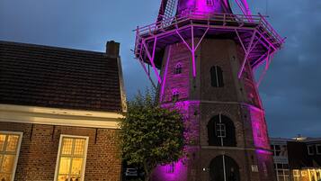 Een windmolen met een bakstenen fundering en een metalen top, verlicht met paarse lichten.
