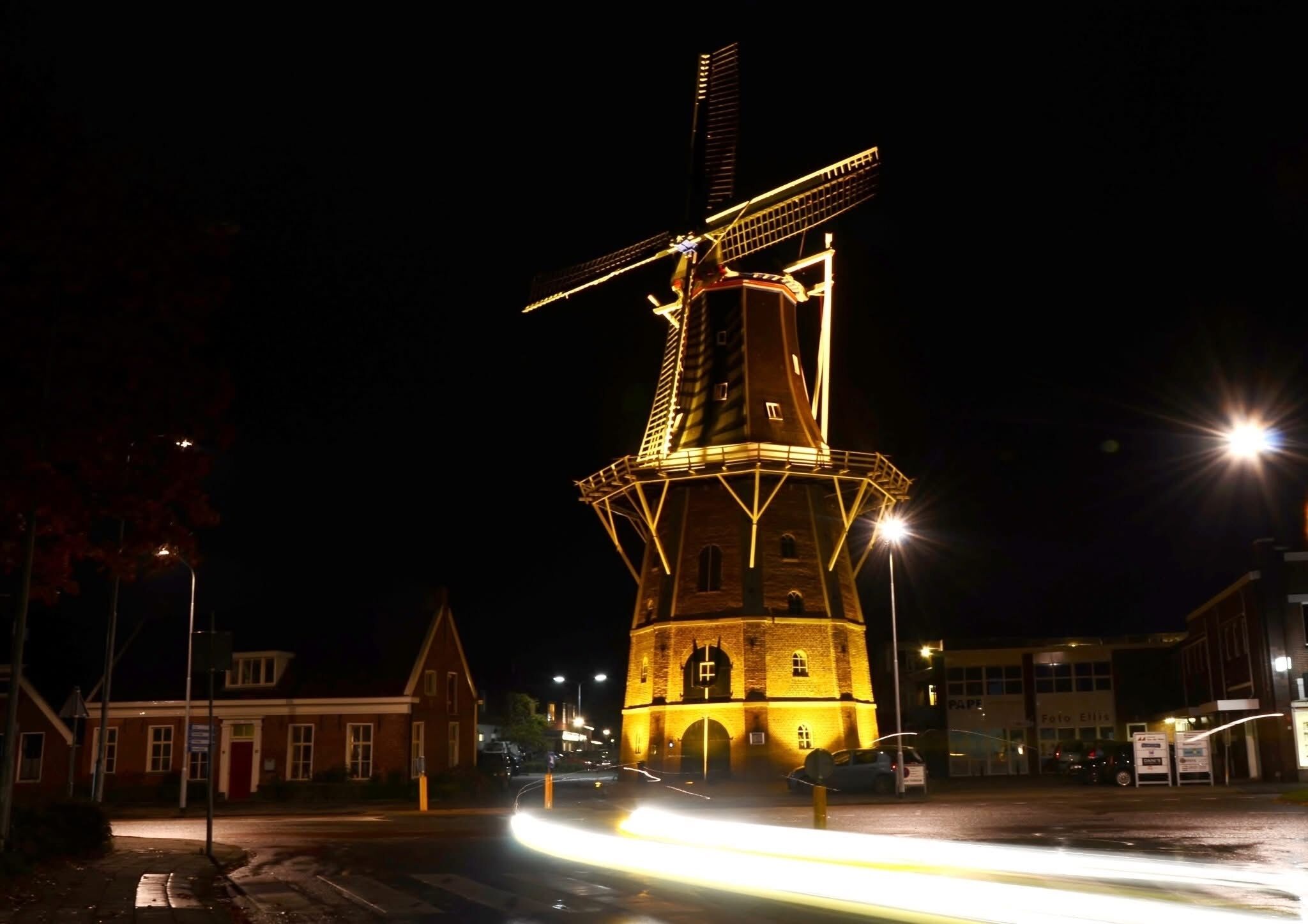 Un molino de viento de noche, iluminado por farolas.