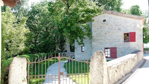 A stone building with red shutters, a metal gate, and a pathway leading to it. - Gîte Petite Maison in the Gers countryside (Castelnau-sur-l'Auvignon)