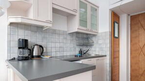 Una cocina moderna con armarios blancos, encimera gris, cafetera y un lavabo.