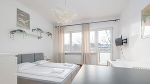 Un dormitorio moderno con cama, mesitas de noche, un escritorio y un amplio ventanal.