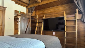 A wooden cabin room with a bed, a TV mounted on the wall, and a ladder leading to a loft area. - Avalanche (Zarnesti)