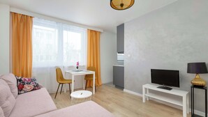 Una sala de estar moderna con un sofá, un televisor sobre un mueble bajo, una mesita y una silla.