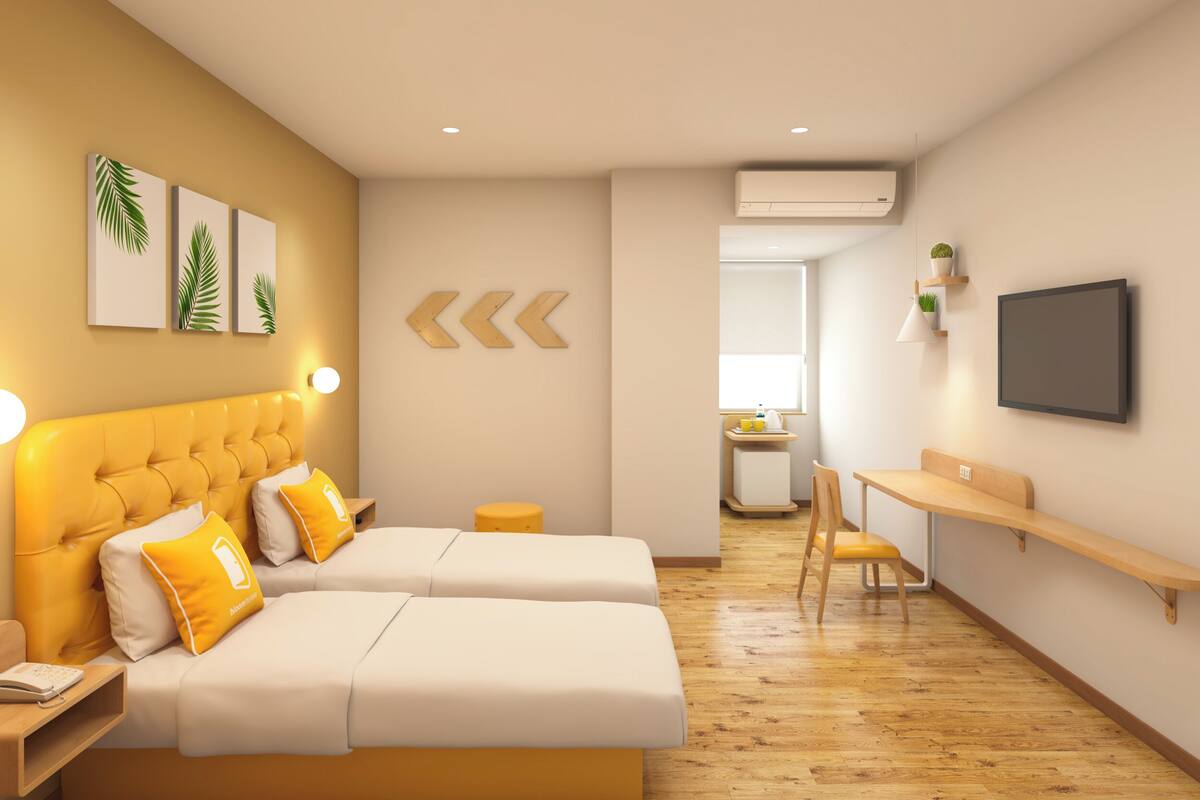 A modern hotel room with two beds, a desk, and a TV.