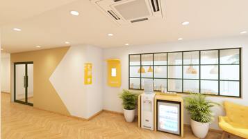 Un'area reception con banco accettazione, distributore d'acqua e piante in vaso.