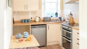 A compact kitchen with a dishwasher, oven, and a window with a view. - Library Cottage near Gorebridge (Gorebridge)