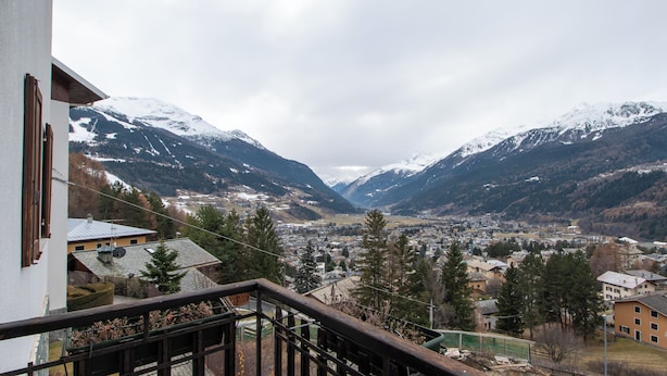 Eine Bergstadt mit schneebedeckten Gipfeln, einem Tal und Blick vom Balkon auf die Stadt und die Berge.