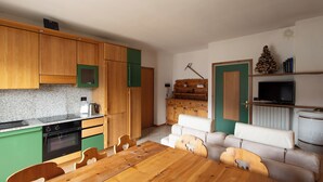 Eine kompakte Küche mit Holzschränken, einem eingebauten Ofen und einem Essbereich mit Holztisch und -stühlen.
