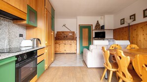 Eine kompakte Küche mit Holzausbau, einem eingebauten Backofen und einem Essbereich mit Holztisch und Stühlen.