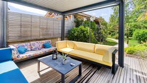 Un patio exterior con un sofá amarillo, un sofá azul y una mesa negra con una planta.