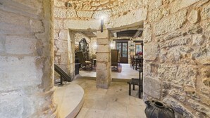 Ein Innenraum mit Steinwänden und einer Treppe, die zu einem Essbereich führt.