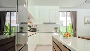 A modern kitchen with white cabinets, a coffee machine, and a fruit bowl on the counter. - Aileen Layan Villa 6/ 4BR Forest/ 2 Minutes Beach (Choeng Thale)