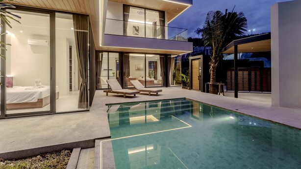 A modern two-story house with a glass-enclosed balcony, a swimming pool, and a well-lit outdoor area. - Aileen Layan Villa 6/ 4BR Forest/ 2 Minutes Beach (Choeng Thale)