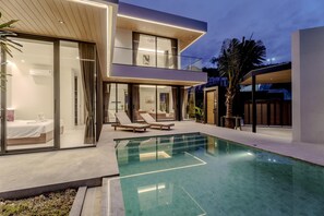 A modern two-story house with a glass-enclosed balcony, a swimming pool, and a well-lit outdoor area. - Aileen Layan Villa 6/ 4BR Forest/ 2 Minutes Beach (Choeng Thale)