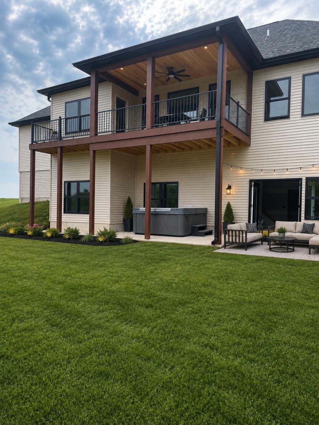 A two-story house with a balcony, a hot tub, and outdoor seating.