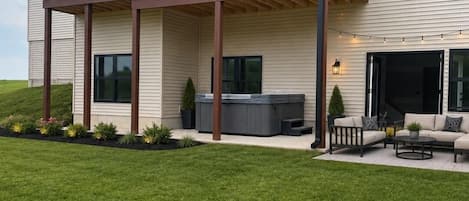 A two-story house with a balcony, a hot tub, and outdoor seating.