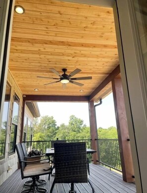 A covered outdoor area with a ceiling fan, a table with chairs, and a view of greenery. - Lakefront house mins from the ARK! Private dock (Dry Ridge)