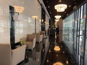 Un moderno vestíbulo de hotel con pared de vidrio, zona de estar e iluminación decorativa.
