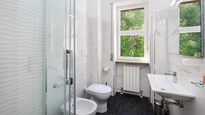 Un baño moderno con cabina de ducha de vidrio, inodoro, bidé y lavamanos con espejo.