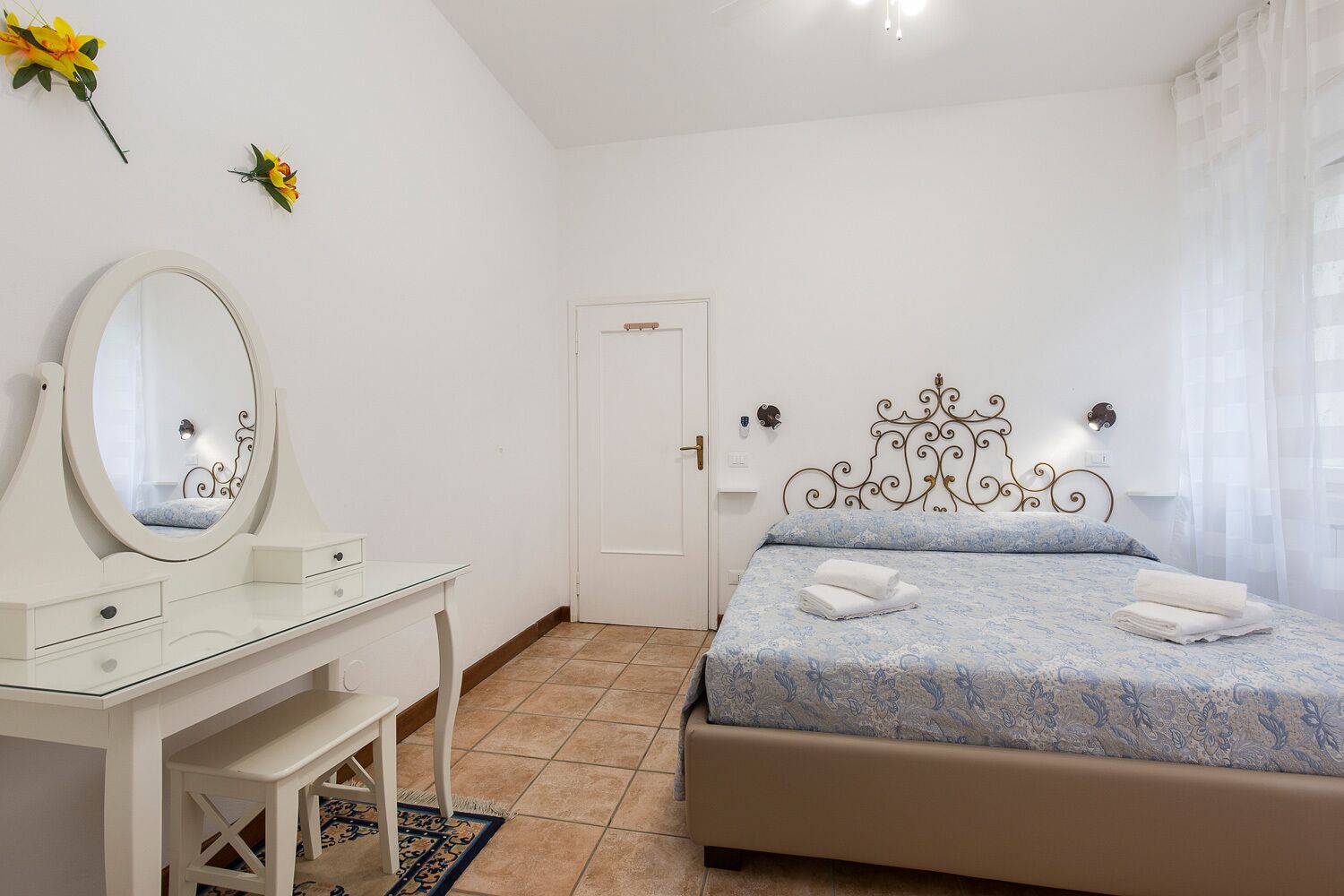 A bedroom with a bed, a dresser, a mirror, and a door.