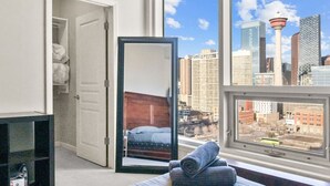 Ein Schlafzimmer mit Blick auf die Stadt, inklusive Bett, Schrank und Fenster.