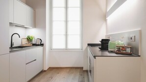 Eine moderne Küche mit weißen Schränken, einem schwarzen Wasserhahn und einem Fenster mit Tageslicht.