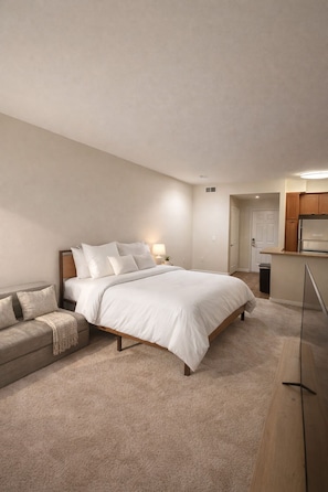 A bedroom with a bed, a nightstand, a bedside table, a sofa, and a wooden floor. - Luxe Marina Del Rey Escape (Marina del Rey)