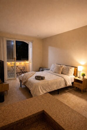 A bedroom with a bed, a nightstand, a lamp, and a sliding glass door leading to an outdoor area. - Luxe Marina Del Rey Escape (Marina del Rey)