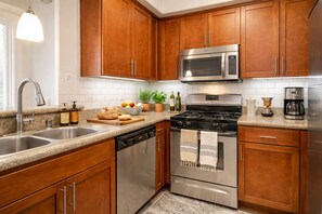 A modern kitchen with wooden cabinets, stainless steel appliances, and a granite countertop. - Luxe Marina Del Rey Escape (Marina del Rey)