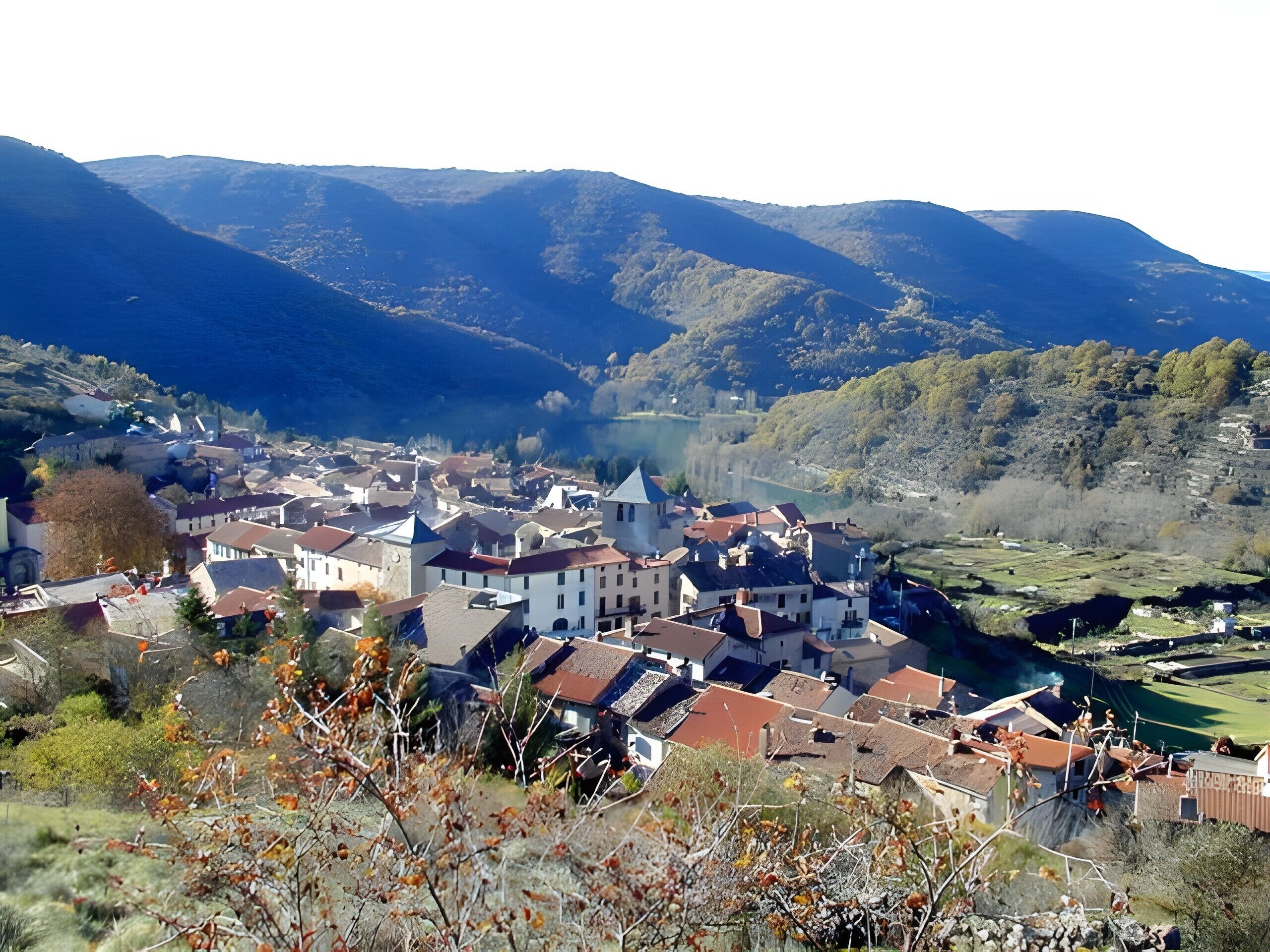 Eine Stadt mit Gebäuden, einem Fluss und Bergen im Hintergrund.