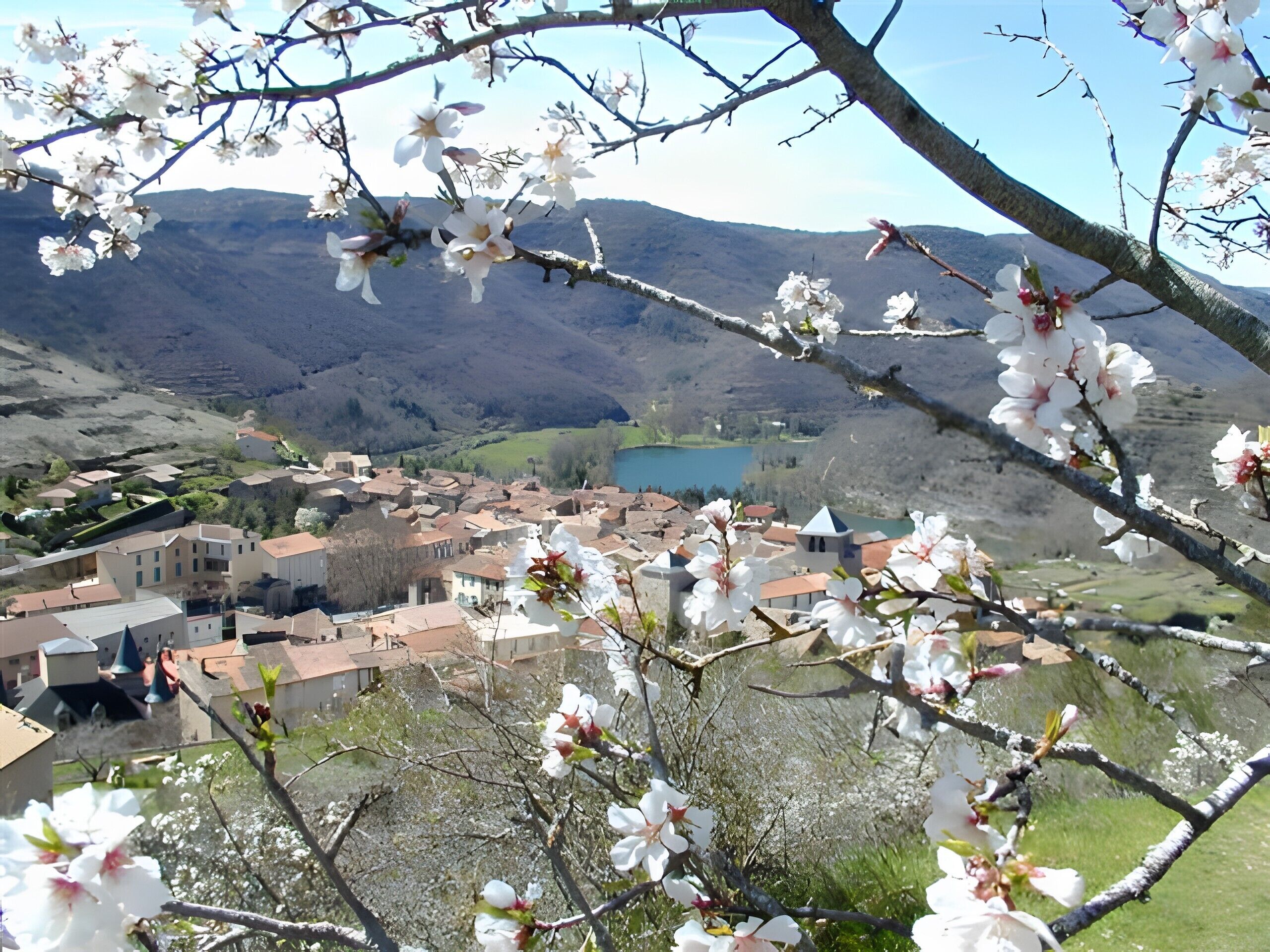 Un pueblo con edificios tradicionales, un lago y montañas al fondo.