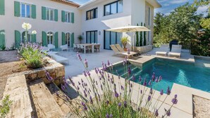 Ein modernes Haus mit Swimmingpool, Sitzgelegenheit im Freien und einem Garten mit Lavendelpflanzen.