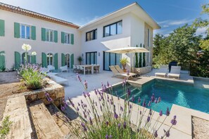 Uma casa moderna com piscina, área de estar externa e jardim com plantas de lavanda.