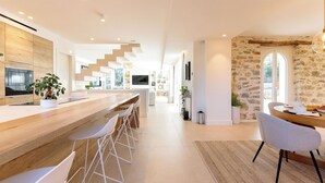 Eine moderne Küche mit einer Holzarbeitsplatte, weißen Barhocker und einer Wand mit Steinverkleidung.