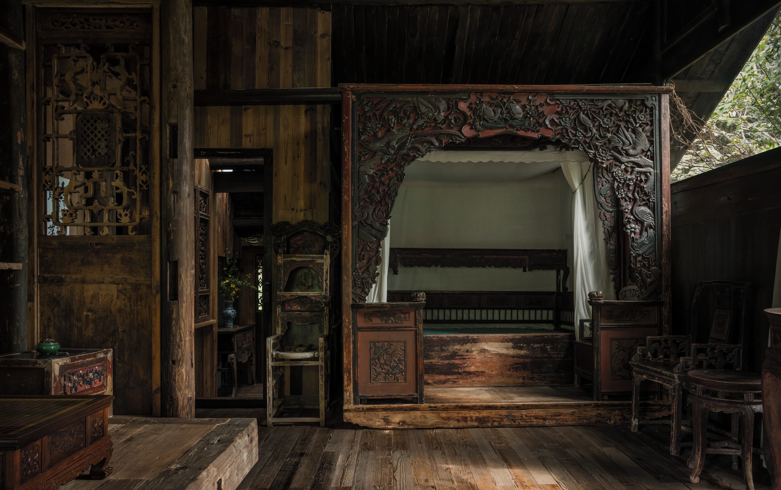 A traditional room with wooden furniture, a bed with a canopy, and a decorative archway.