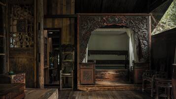 A traditional room with wooden furniture, a bed with a canopy, and a decorative archway.