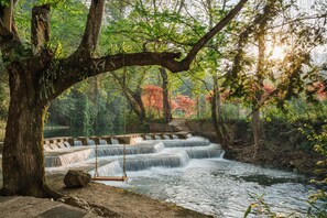 A waterfall with a swing, surrounded by trees and a stone bridge. - Fanjingshan Ansu Homestay (Tongren)