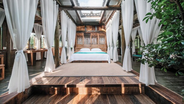 A traditional room with a wooden bed, white curtains, and a view of a traditional building. - Fanjingshan Ansu Homestay (Tongren)
