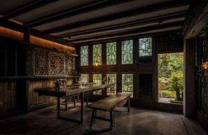 A traditional room with a wooden table, bench, and large windows with intricate lattice designs. - Fanjingshan Ansu Homestay (Tongren)