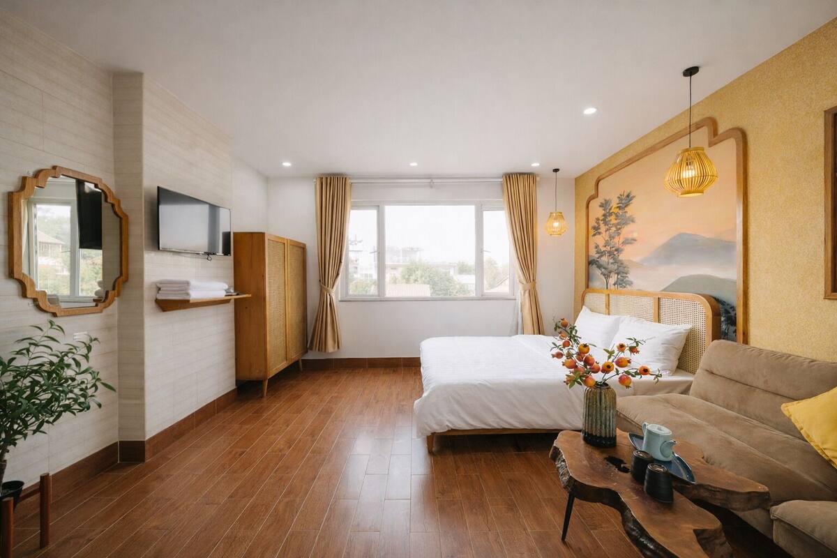 Une chambre d’hôtel moderne équipée d’un lit, d’un canapé, d’une télévision, d’une armoire et d’une grande fenêtre.