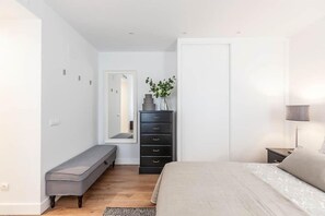 A bedroom with a bed, a dresser, a bench, a mirror, and a plant. - Splendid apartment next to Gran Vía (Madrid)
