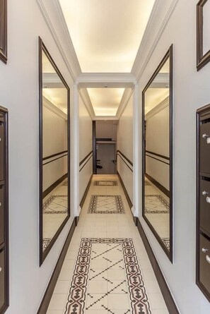A hallway with mirrored walls, a patterned floor, and a door at the end. - Splendid apartment next to Gran Vía (Madrid)