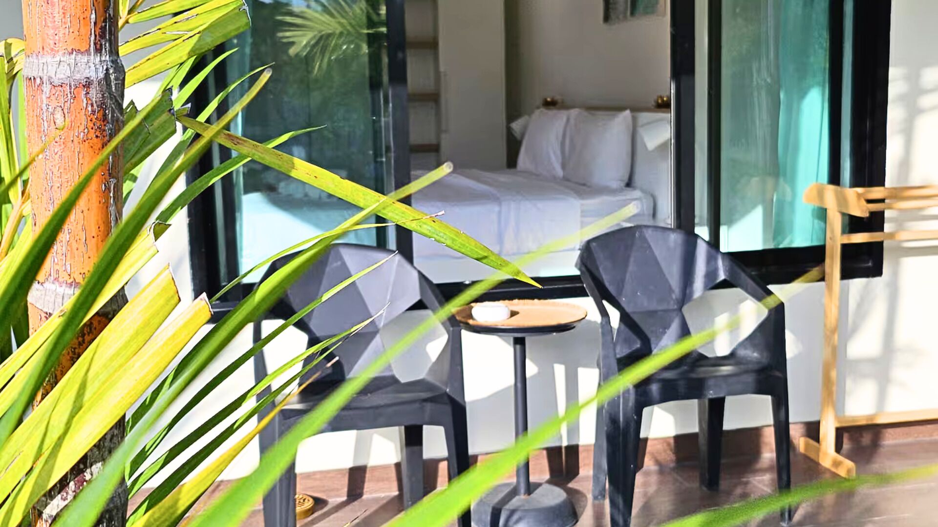 A room with a bed, a small table, two chairs, and a window with curtains.