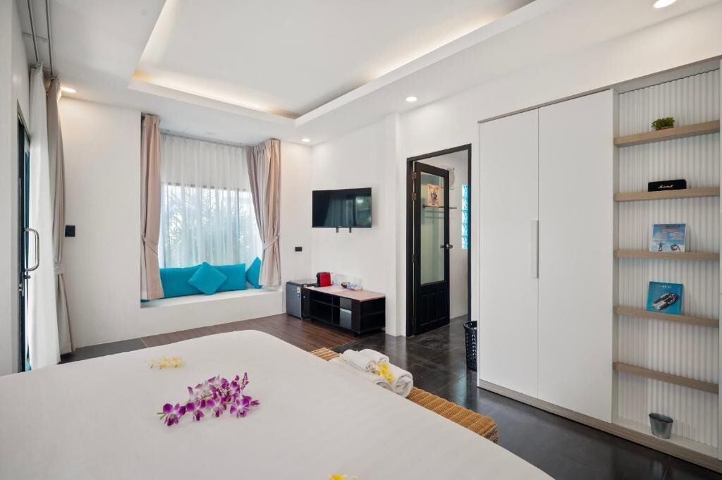 Une chambre d’hôtel moderne avec un grand lit, un téléviseur fixé au mur, un petit bureau et une armoire.